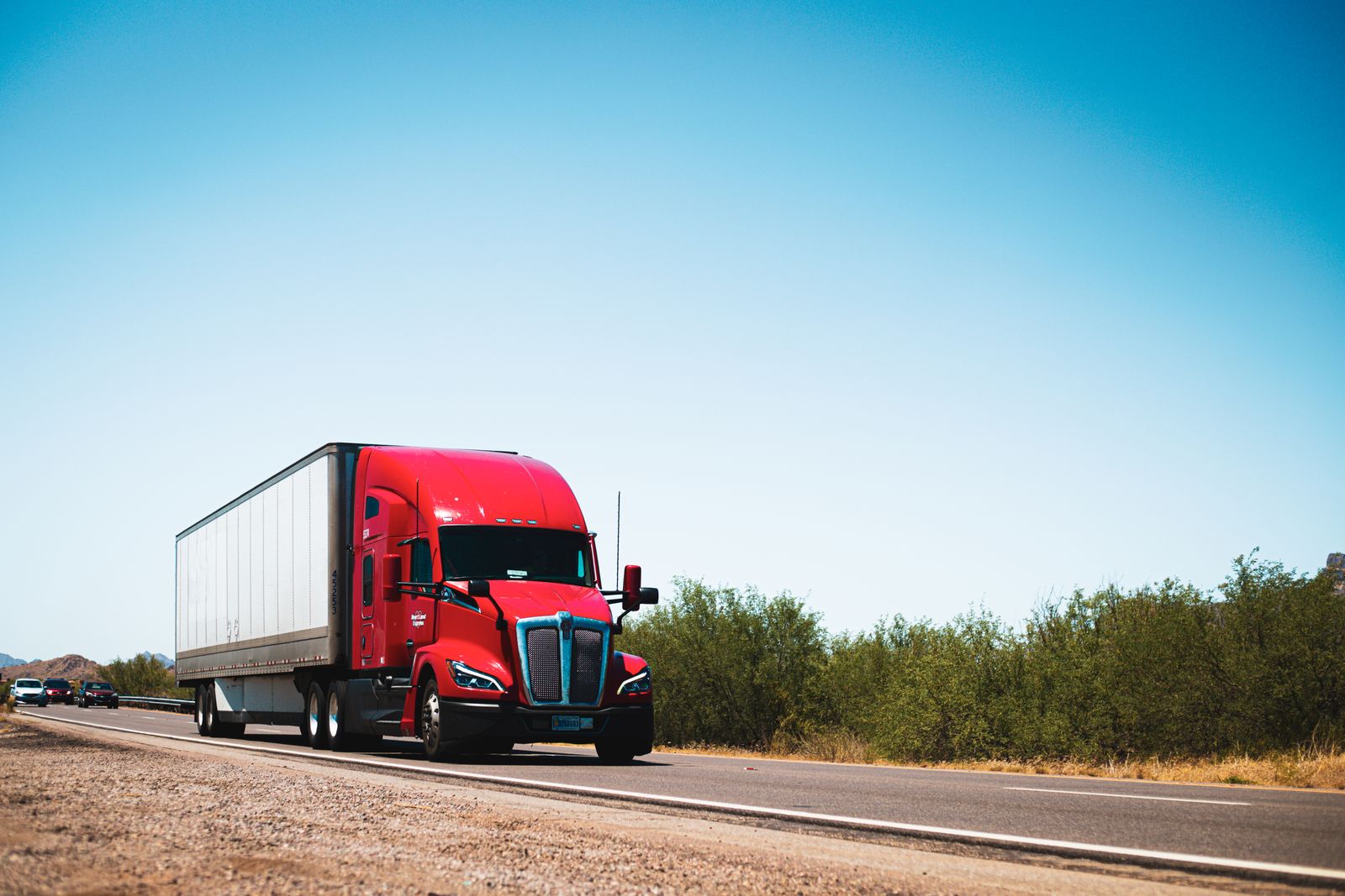 A red American long-haul truck on an open western desert highway